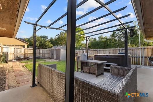 2305 Canyon Creek Dr, Temple, TX 76502 - view of patio / terrace with a hot tub, a fenced backyard, a storage shed, and an outdoor structure