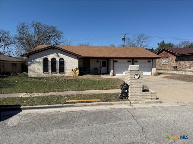 view of front of property with a garage, a front yard, brick siding, and driveway