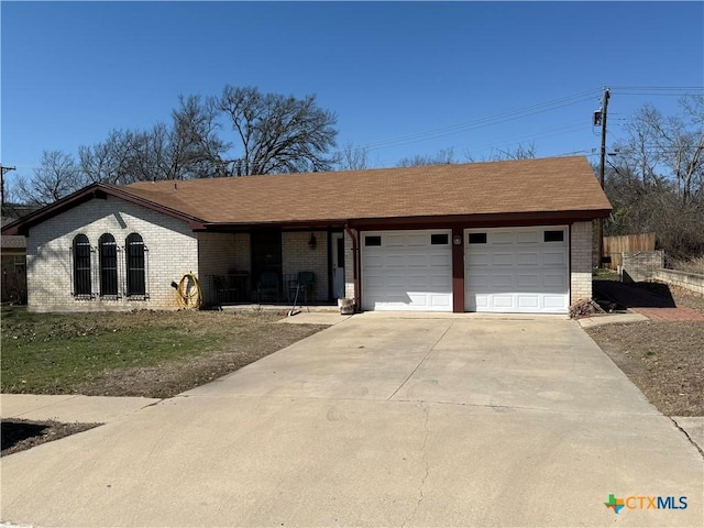 single story home featuring concrete driveway, brick siding, an attached garage, and roof with shingles