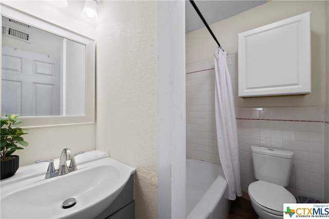 full bathroom featuring shower / tub combo with curtain, vanity, toilet, and tile walls