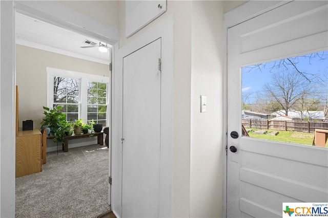 doorway to outside featuring carpet, ceiling fan, and crown molding