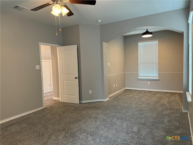 carpeted empty room featuring arched walkways, visible vents, and baseboards