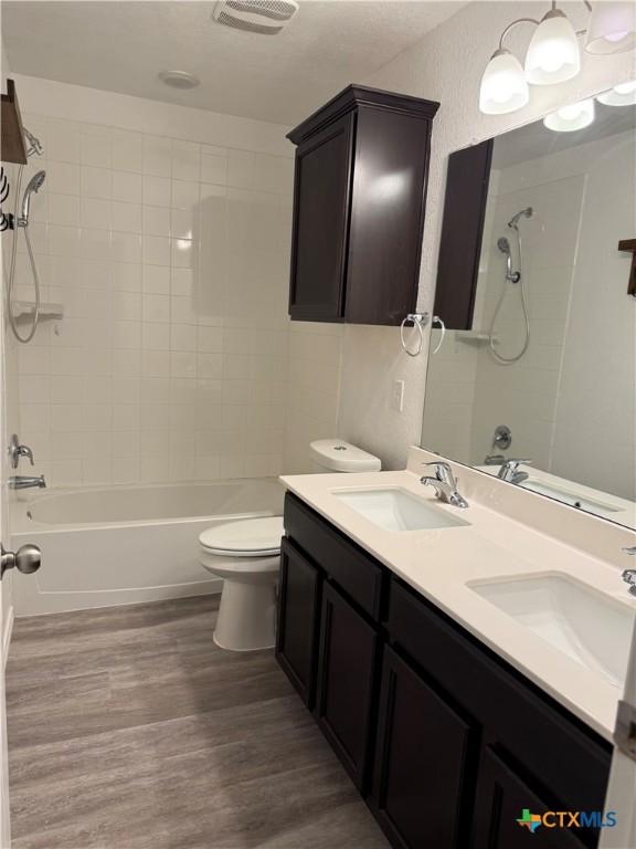 full bathroom with tub / shower combination, a sink, toilet, and wood finished floors