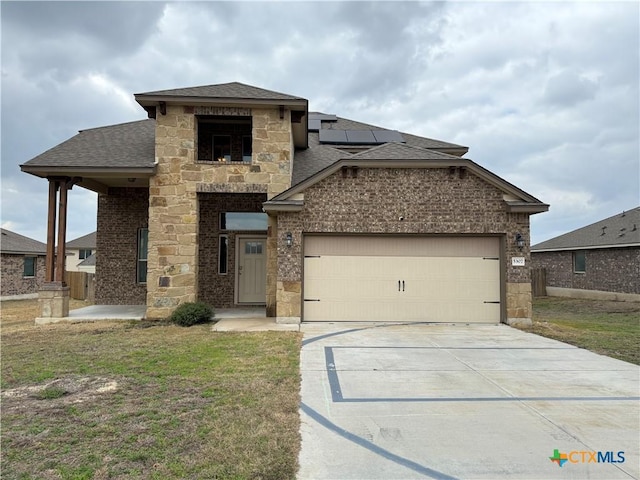 view of front facade with roof with shingles, brick siding, concrete driveway, roof mounted solar panels, and a garage