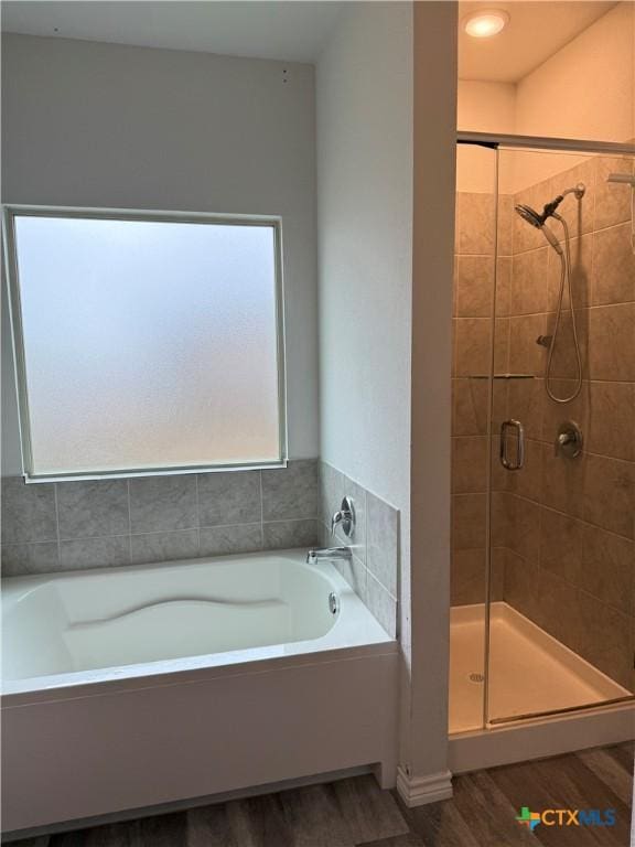 full bath featuring a garden tub, a shower stall, and wood finished floors