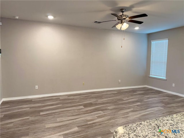 spare room with ceiling fan, baseboards, and wood finished floors