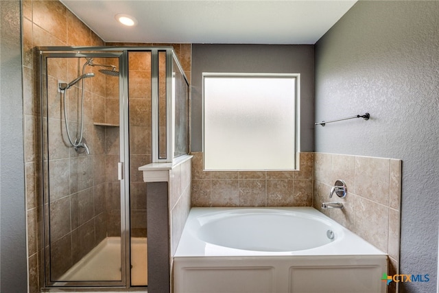 7631 Sterling Mnr, Converse, TX 78109 - full bathroom with a bath, a shower stall, and a textured wall