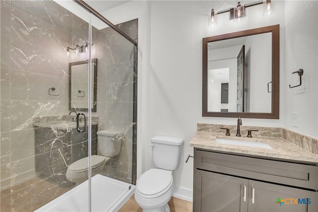 bathroom featuring toilet, vanity, and a shower with shower door