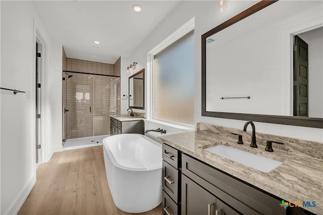 bathroom featuring independent shower and bath, vanity, and hardwood / wood-style flooring