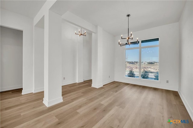 unfurnished dining area featuring an inviting chandelier and light hardwood / wood-style floors