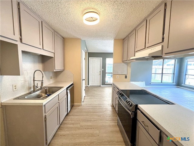 105 Kensington Dr, Victoria, TX 77901 - kitchen featuring appliances with stainless steel finishes, under cabinet range hood, a sink, light wood finished floors, and a textured ceiling