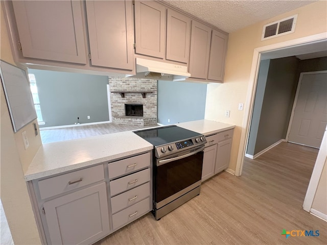 105 Kensington Dr, Victoria, TX 77901 - kitchen featuring stainless steel electric range oven, under cabinet range hood, gray cabinets, and a textured ceiling