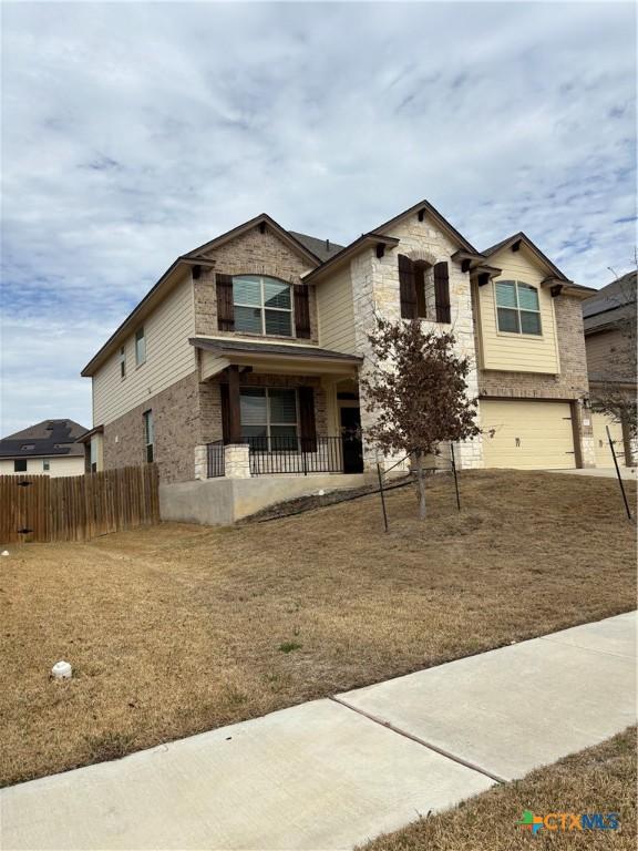 view of front of property with a garage, stone siding, and fence