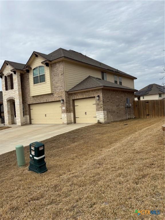 view of front of property with brick siding, fence, concrete driveway, a front yard, and stone siding