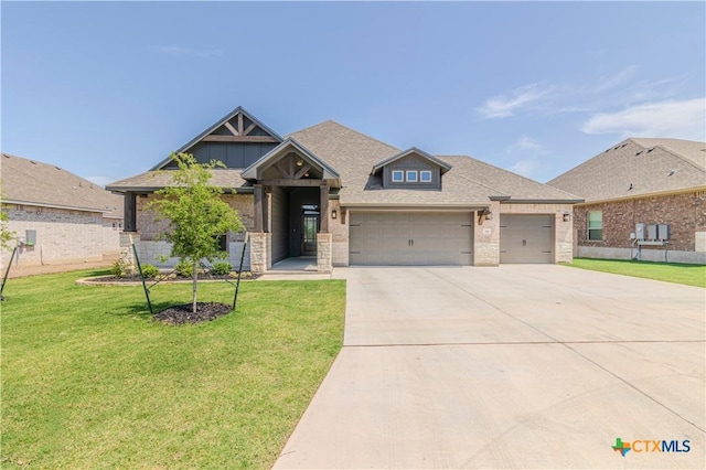711 Saddlehorn Dr, Temple, TX 76502 - craftsman-style house with driveway, an attached garage, stone siding, and a front lawn