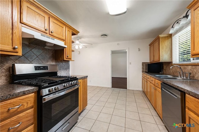 kitchen with black dishwasher, dark countertops, a sink, gas range, and under cabinet range hood