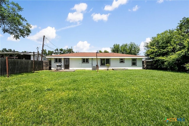 rear view of property featuring a lawn and fence private yard