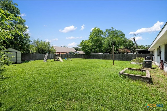 view of yard featuring an outbuilding, a playground, a vegetable garden, a storage unit, and a fenced backyard