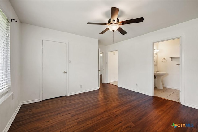 unfurnished bedroom with dark wood-type flooring, a sink, and baseboards