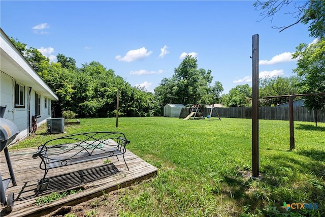 view of yard with a playground, central air condition unit, a storage unit, a fenced backyard, and an outdoor structure