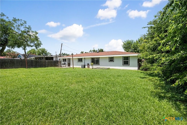 rear view of property with a yard and fence