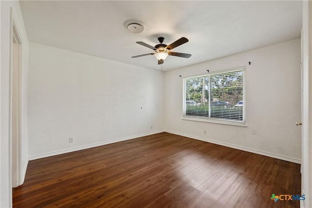 spare room featuring ceiling fan, dark wood-style flooring, and baseboards