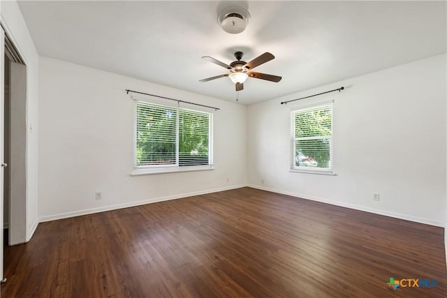 spare room featuring a ceiling fan, dark wood-style flooring, and baseboards