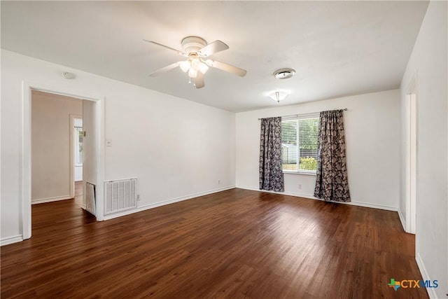 empty room with dark wood-style flooring, visible vents, and baseboards