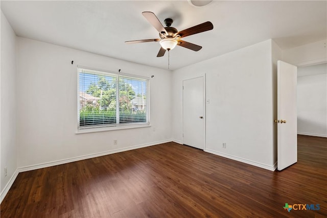 empty room featuring dark wood-style floors, baseboards, and a ceiling fan