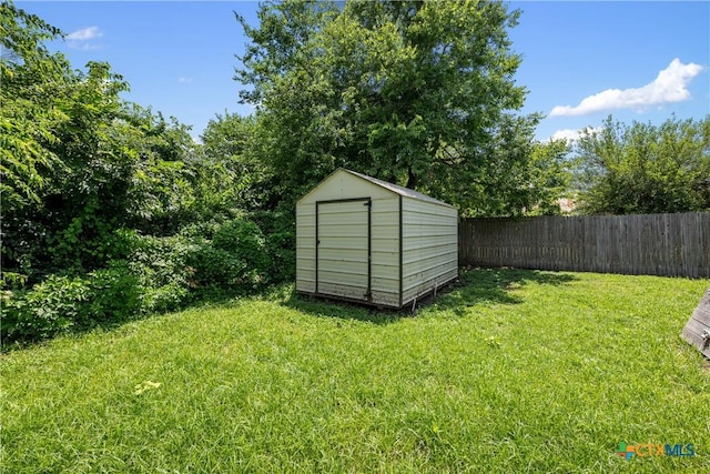 view of yard featuring an outdoor structure, fence, and a storage unit