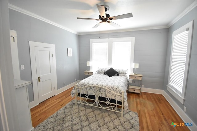 bedroom with ceiling fan, crown molding, baseboards, and wood finished floors