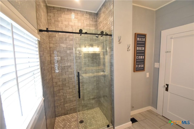 bathroom with a stall shower, crown molding, and baseboards