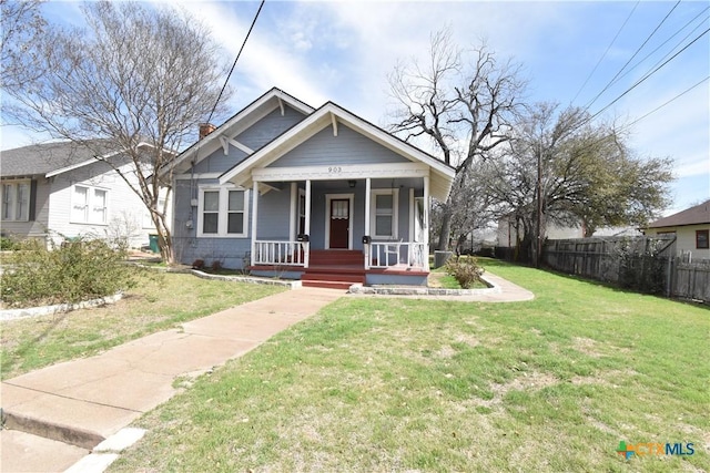 bungalow-style house featuring a front lawn, fence, covered porch, and a chimney