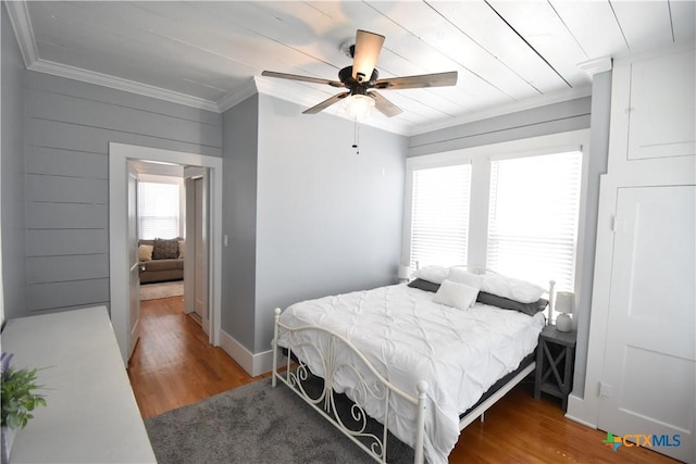 bedroom with crown molding, multiple windows, and wood finished floors