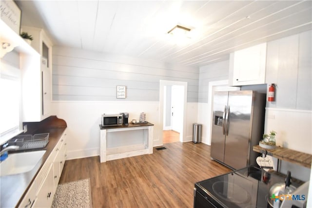 kitchen featuring a sink, stainless steel appliances, wood finished floors, and white cabinetry