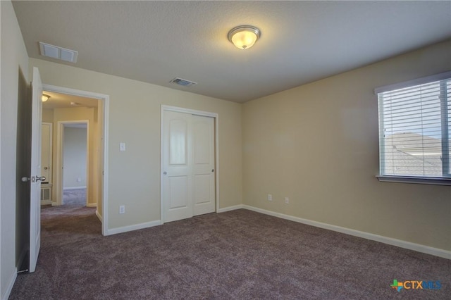 unfurnished bedroom featuring a closet and dark carpet