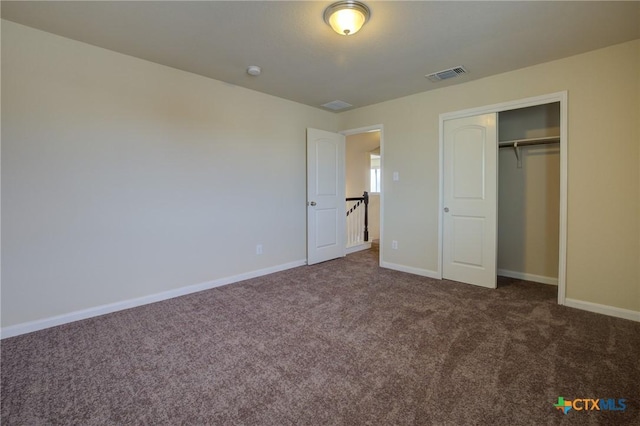 unfurnished bedroom featuring a closet and dark carpet