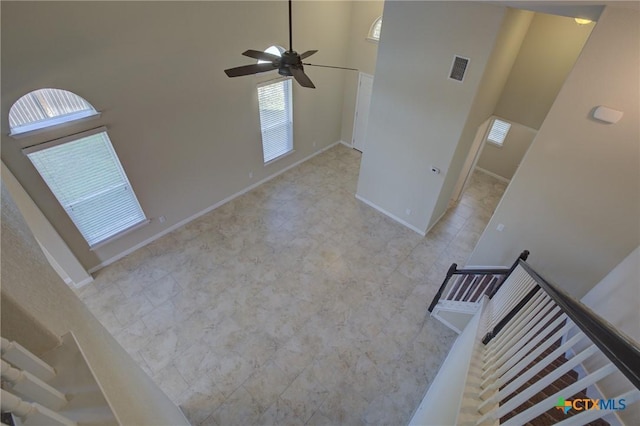 unfurnished living room featuring a towering ceiling and ceiling fan