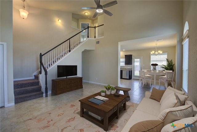 tiled living room featuring ceiling fan with notable chandelier and a high ceiling