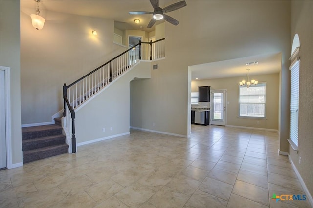 unfurnished living room with a towering ceiling and ceiling fan with notable chandelier