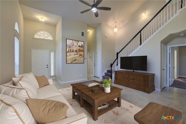 living room with a towering ceiling and ceiling fan