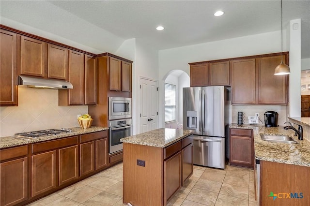 kitchen with appliances with stainless steel finishes, tasteful backsplash, pendant lighting, a kitchen island, and sink