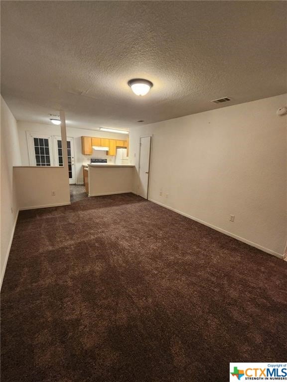 interior space with a textured ceiling and dark colored carpet