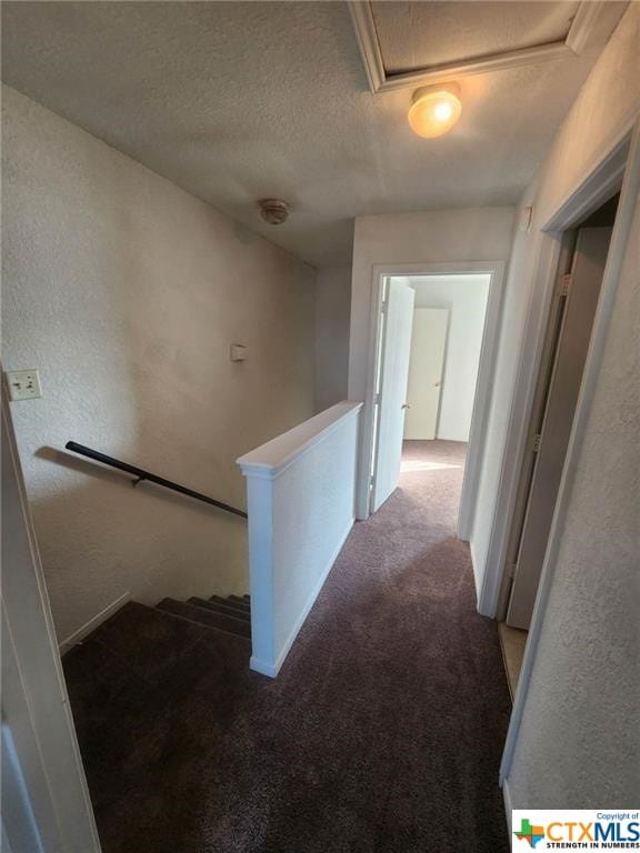 corridor with a textured ceiling and carpet flooring