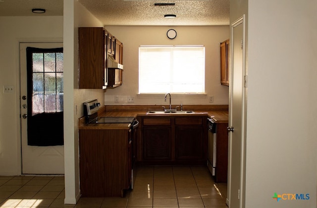 kitchen with electric stove, sink, light tile patterned floors, and a textured ceiling