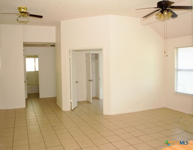 unfurnished room with ceiling fan, light tile patterned flooring, a textured ceiling, and vaulted ceiling