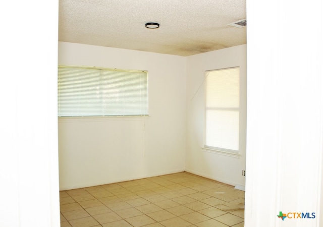 tiled spare room featuring a textured ceiling