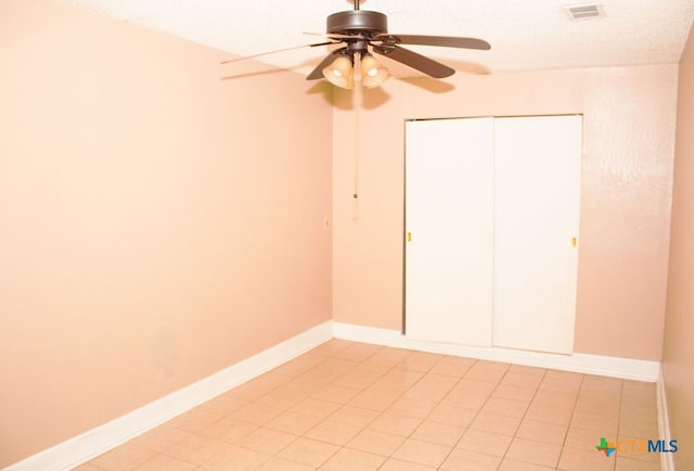 unfurnished bedroom with ceiling fan, light tile patterned floors, a textured ceiling, and a closet