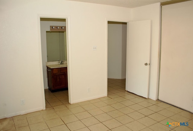 unfurnished bedroom featuring light tile patterned floors and connected bathroom