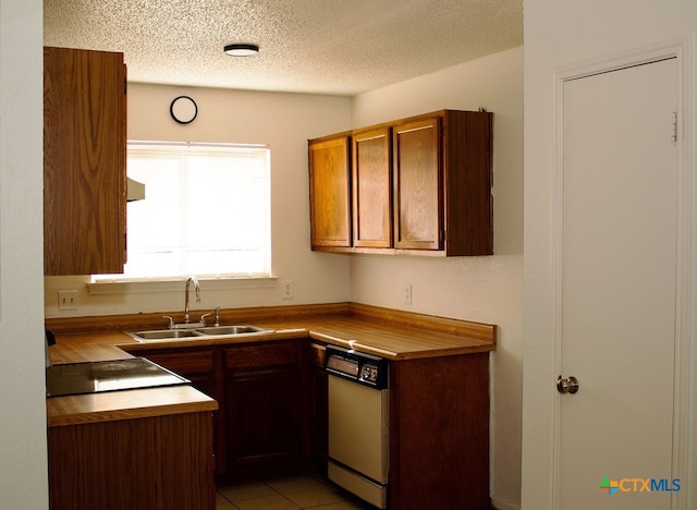 kitchen with light tile patterned flooring, a textured ceiling, dishwasher, and sink